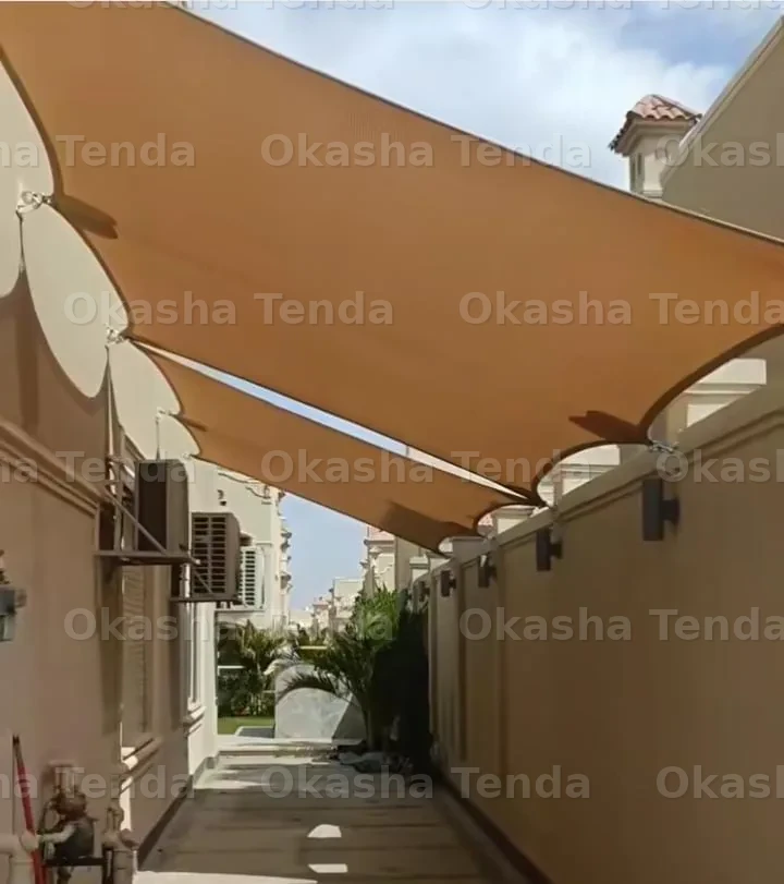 تندات قماشية مظللة ممتدة على ممر خارجي بين جدران مبانٍ سكنية