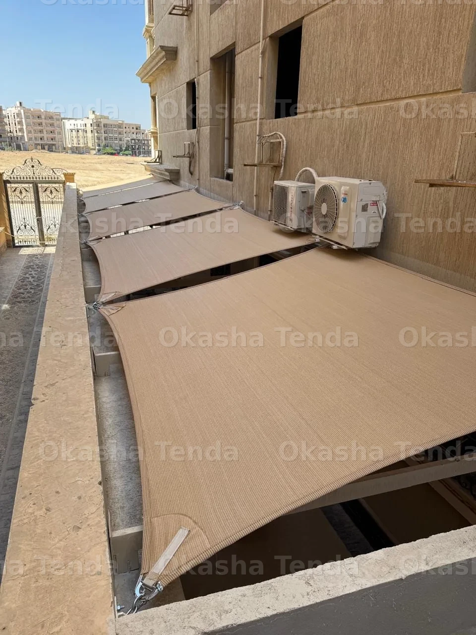 مظلات قماشية مثبتة على شرفة مبنى بجانب مكيفات هوائية