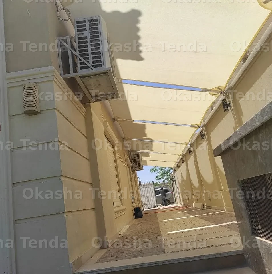 مظلة قماشية مثبتة على جدار مبنى تغطي ممر جانبي ضيق